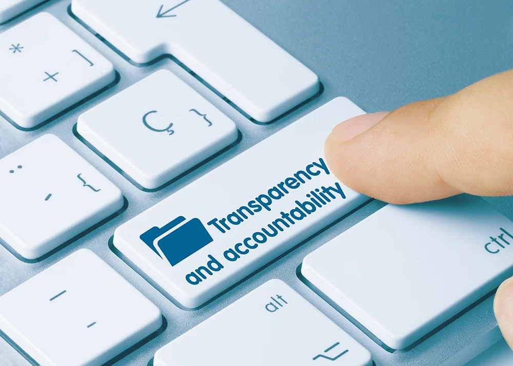 Finger pressing a keyboard key labeled "Transparency and accountability."
