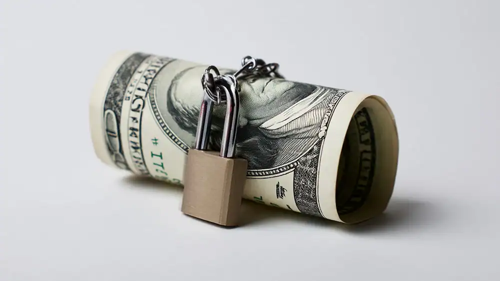 Rolled-up dollar bill locked with a padlock.