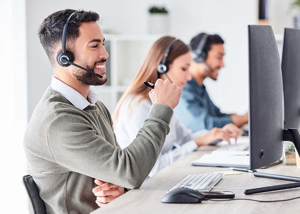 Smiling customer support agents wearing headsets at their desks.